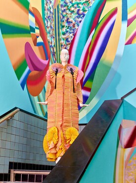 Fong-Leng, Coat ‘Rups’, 1975, worn by  Mathilde Willink, Kunstmuseum Den Haag; in the back mural by Hadassah Emmerich, 2026. Photo: Alice de Groot