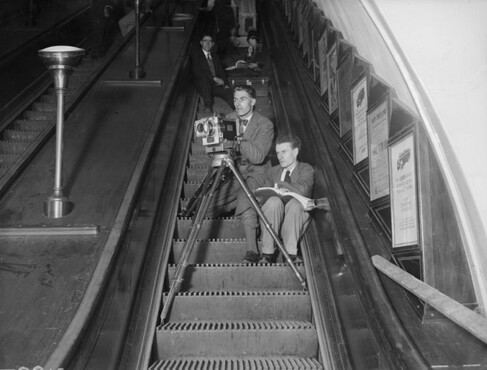 Britse regisseur Anthony Asquith (1902-1968), rechts, regisseert de film ‘Underground’ vanaf een roltrap in de Londense metro, 1928